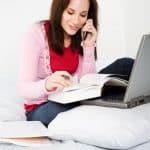 person studying text book at laptop