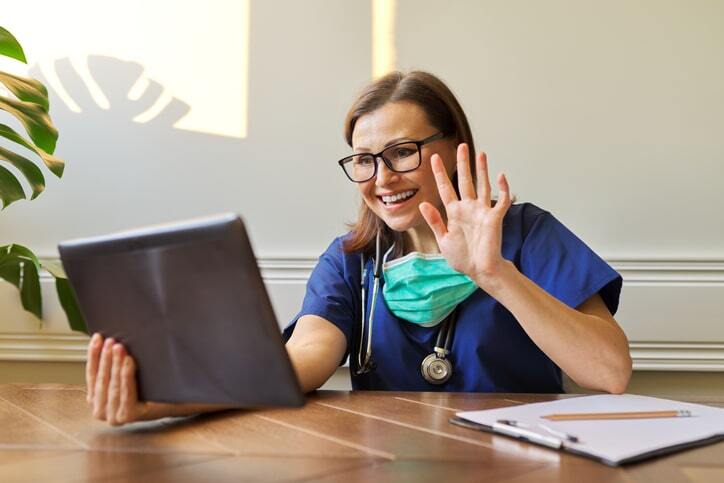 doctor waving at tablet during telemedicine visit